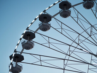 Ferris Wheel with empty booths close up in Amusement park on a clear sky. Summer fun for the whole family