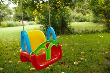 bunte Kinderschaukel auf einer Wiese mit Fallobst