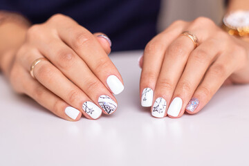 
Beautiful female hands with fashion manicure nails, white and silver gel polish, stars design
