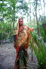 Bangladeshi hindu religious woman smiling in outdoor village environment wearing traditional dress 