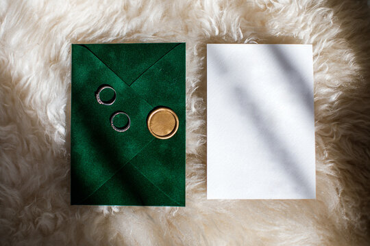 Two Wedding Rings On A Green Invitation Envelope