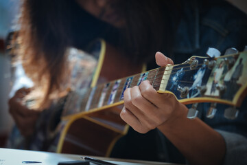 Close up on hand of asian musician who have long hair is playing acoustic guitar and change chord...