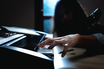 Close up on fingers of asian musician at the piano keys and holding acoustic guitar. Pianist...