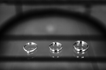 Three wedding rings on a glass surface