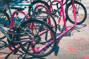 Fahhräder angekettet an einem pinkfarbenen Fahrradständer, saubere Fortbewegung, Umweltschutz