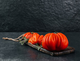 A group of Costoluto big tomatoes with oregano on a grey background, space for text