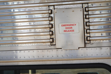 Silver hatch door cover over emergency door release on a train car