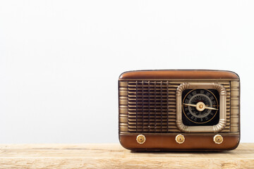 Retro radio receiver on a wooden surface and white background.  Vintage radio with copyspace.