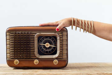 Hand with bracelets and painted nails on an old radio, with dials and push buttons. Listening music...