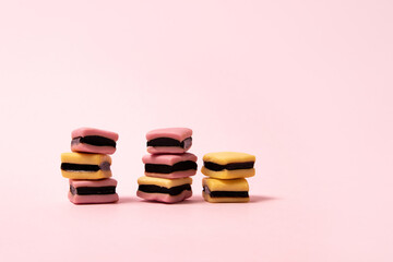 Piles of pink and yellow licorice candies on pink  background