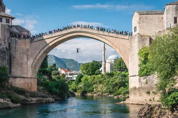 Tuinposter Stari Most MOSTAR, BOSNI EN HERZEGOVINA - 21 september 2021: De mens springt duikend van Stari most, Old Bridge, in Mostar. Bosnië-Herzegovina