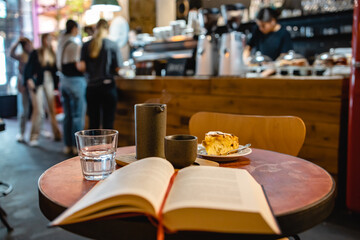 Sunday brunch with coffee and peach scone in a third-wave cafe reading book in horizontal shot