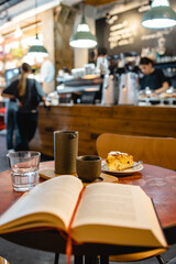 Sunday brunch with coffee and peach scone in a third-wave cafe reading book in vertical shot