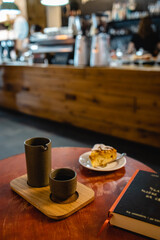 Brunch with coffee and peach cake and book in a modern cafe with a blurred boke counter in the background