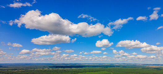 Blue sky panorama with clouds over tops of green trees. Blue sky and white cloud soft. White clouds background.