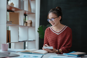 Young business women working and calculating on laptop with happy and smile face on office spec.