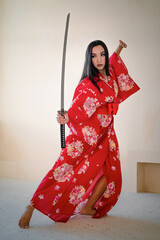 Young beautiful asian girl in the red kimono with the katana sword. - obrazy, fototapety, plakaty