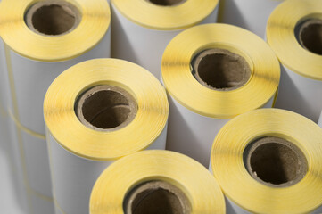 Rollers with a white self-adhesive label for printing labeling information. Ribbon with white label on cardboard spools. Products of the printing house. Selective focus