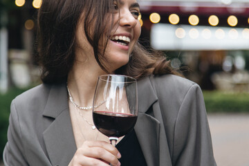 A young woman with a glass of wine outside near a restaurant.