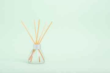Aromatic Incense, oil diffuser with reed sticks on green background. Closeup, copy space
