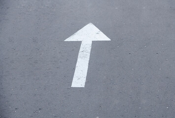 White arrow sign on the street. Directional arrow painted on pavement asphalt. Direction for...