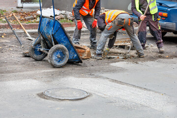 A team of road workers are repairing a sewer manhole on the carriageway.