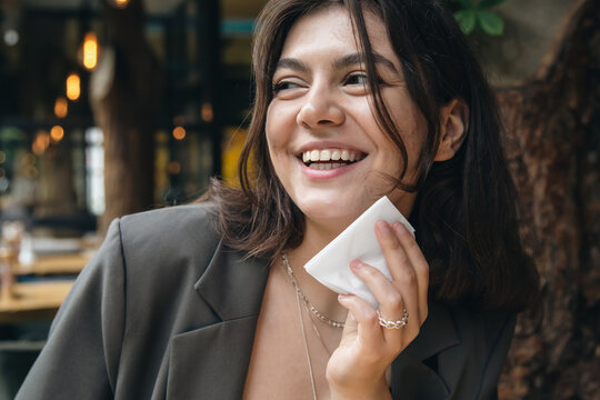 Happy young woman with a napkin near her mouth in a restaurant.