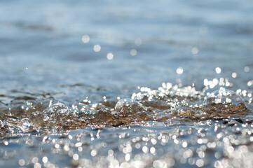 close-up wave on the lake on a sunny day. water background, selective focus with bokeh. summer mood