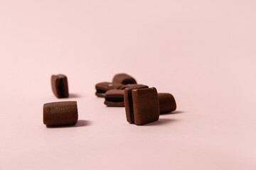 Chocolate licorice candies on pink background. Shallow dof