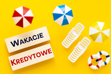 Wakacje Kredytowe in Poland, Loan Holidays Written in Polish, Miniature sunbeds, umbrellas on the...