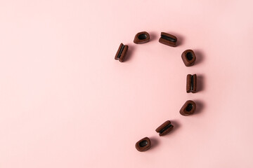 Half heart licorice brown candies on pink pastel background