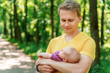 A father walks in a summer park with his baby kid