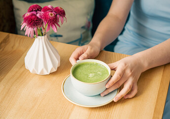 Close-up, a cup with green matcha drink in female hands.