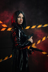 Naklejka premium Young girl in the leather wear with the gun in the neon lights. Superhero concept.