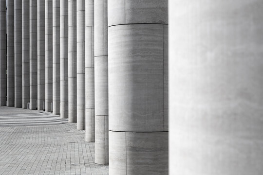 Series of partially illuminated columns made of modern materials standing in semicircle