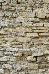 Masonry wall of old stone blocks of limestone. Background texture of ancient brick wall. Full frame. Vertical photo. Selective focus.