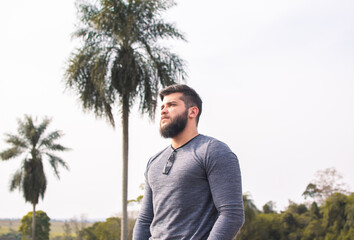 Portrait of a strong man with a beard with trees in the background