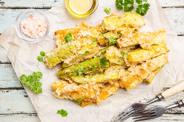 Zucchini sticks in batter, baked in oven over wooden background, top view