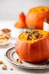 Tasty baked pumpkin stuffed with rice, vegetables, cashews and dried fruits on white background