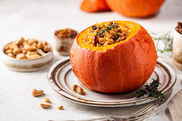 Tasty baked pumpkin stuffed with rice, vegetables, cashews and dried fruits on white background