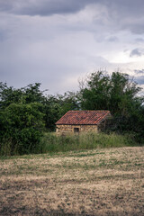 Fototapeta premium Stone hut in a field on a cloudy spring day, Auvergne, France