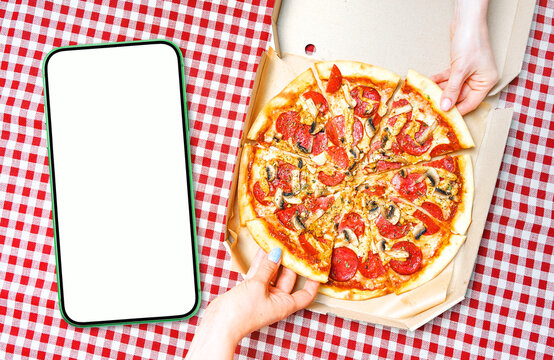 Pizza, hands and empty cellphone for your app design. Blank empty smartphone with white screen near the hands holding pizza slices. View above.