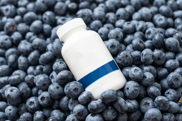 Bottle with medicine on the background of a large blueberry
