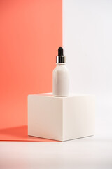 Serum or essential oil bottle on white and pink background. Bright shadows. Beauty product concept.