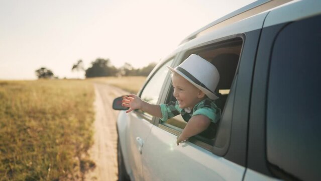 Happy family.Family travel on rural road. Summer vacation in nature. Road trip for children and parents. Toddlers wave from car window Children look out window at sky. Happy family concept.