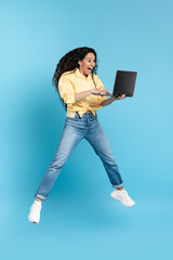 Excited Middle Eastern Lady Holding Laptop Jumping Over Blue Background