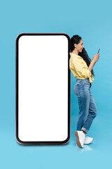 Female Using Smartphone Leaning On Huge Phone Screen, Blue Background