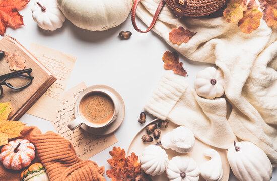 Warm coffee with pumpkins and colorful leaves over white background top view. Stylish autumn flat lay. Hello fall. Cozy warm image