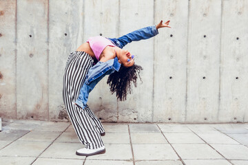 teenage woman dancing in the city outdoors, generation z trendy urban dance sport in blue jacket...