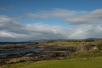 A rainbow sets on the rugged coastline of Ayrshire 
